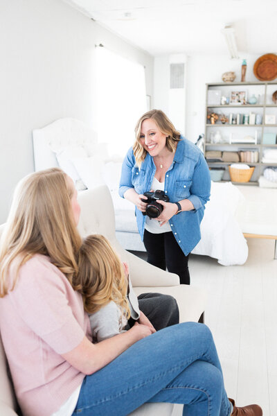 Tiffany Hix holding a camera in her studio looking at her clients during family pictures in her Boise Idaho photography studio