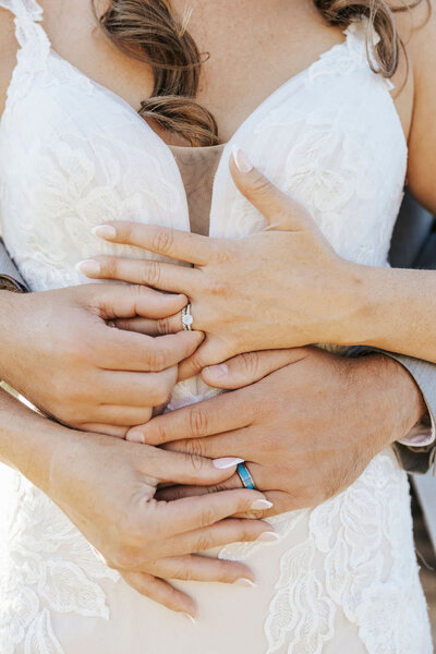 A close up of someone wrapping their arm around another person both showing off wedding rings