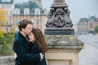 Man kissing woman’s forehead on a romantic couple photoshoot near Notre-Dame and Pont Neuf captured by Paris photographer Rachael Laporte