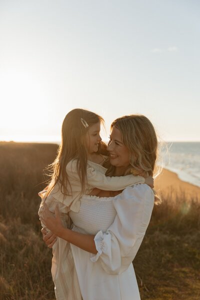 mom holding daughter on beach for lifestyle family session in pei
