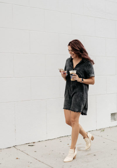 Woman walking downtown with a coffee and phone in her hand while smiling.