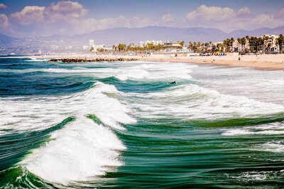 A stunning coastal city with waves crashing along the shore, perfect for luxury travelers seeking urban adventure and seaside escapes