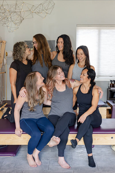 Team photo of a pilates team in Boulder CO.They are all looking at each other and smiling. 