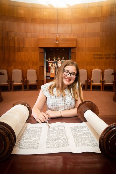 Charlotte smiling while reading torah at Temple Emanuel in Newton, MA at her Bat-Mitzvah