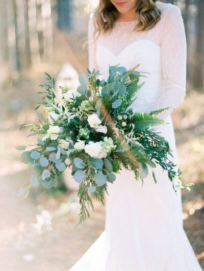 Bride holding large bouquet of green and white florals at Long Island wedding