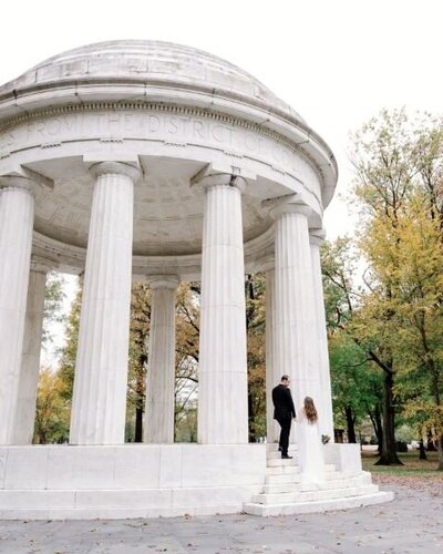 Couple pose in front of the middle of the DC war memorial