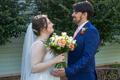 Bride and groom looking at each other while holding a floral bouquet