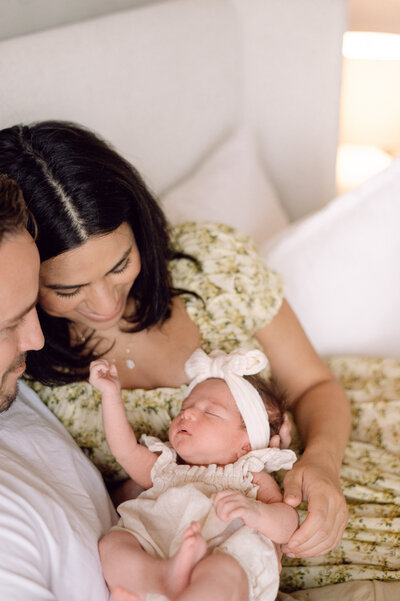 Parents look lovingly at their newborn baby dressed in neutral tones during a lifestyle session photographed by a Northern Virginia family photographer.