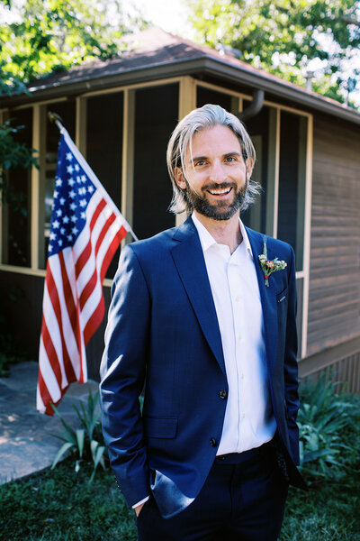 Groom stands by American flag in Boulder Colorado's Chautauqua