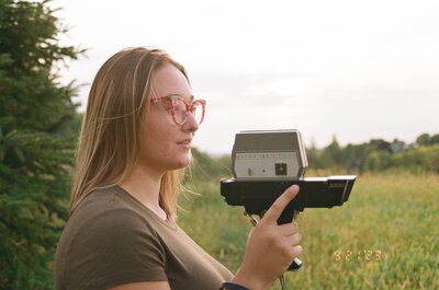 brianna kirk looking off into the distance admiring the sunset while holding super 8 camera