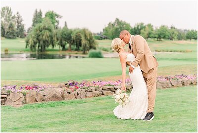 Bride and groom kissing in an open golf course with a small pond and willow tree in the background