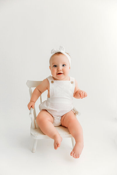 baby on white backdrop in white romper for milestone session at phoenix photography studio