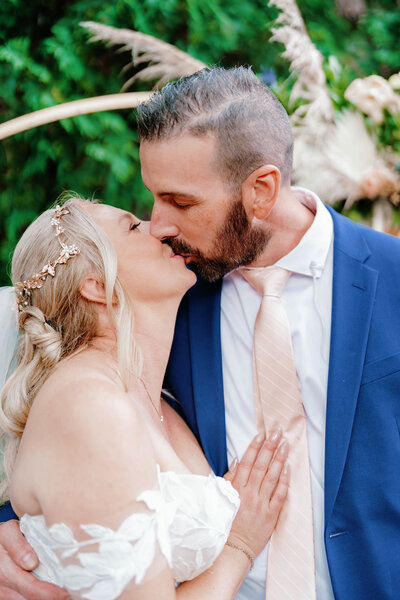 blond bride and brunette groom kiss closeup