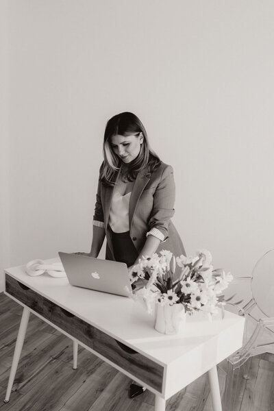 Woman browsing on a laptop in beige suit