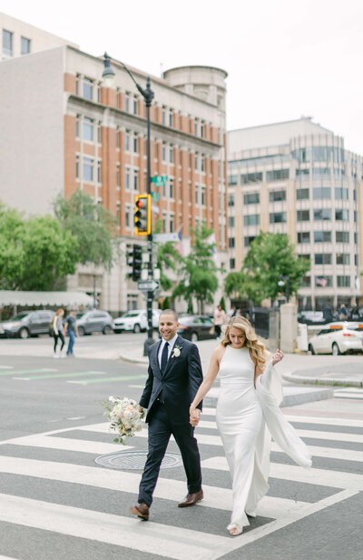 A bride and groom walk across the road in downtown DC.