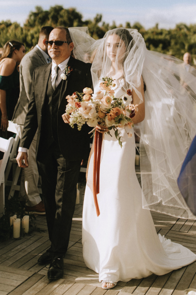 Bianca walks with her dad down the aisle while holding an incredible bouquet from Molly