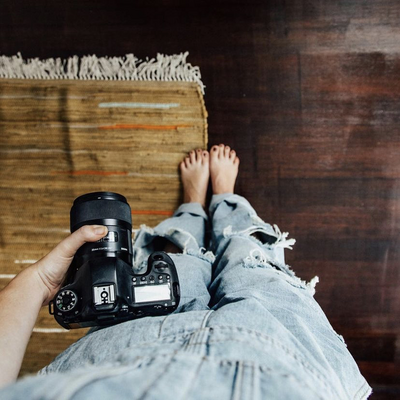 Cute women holding camera in blue jeans and cute rug