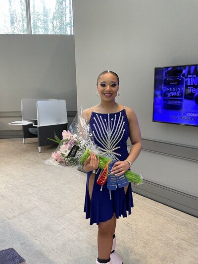 Morgan owner of Curtsy Ballroom in a blue dress holding a pink flowers