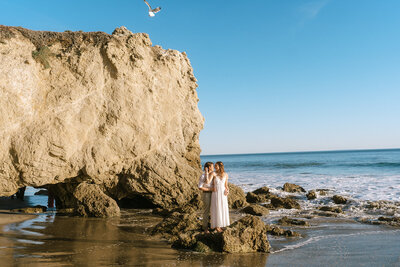 brides kiss on rock on beach