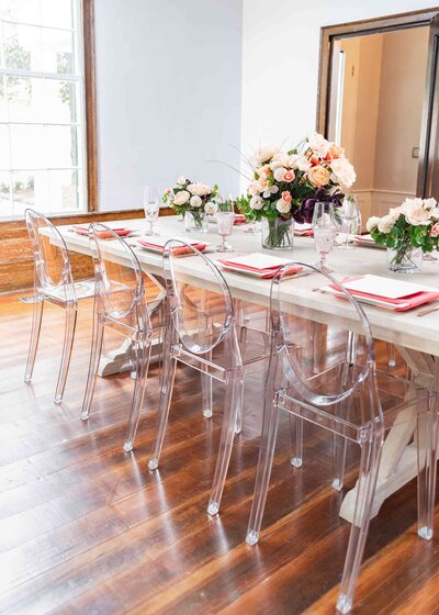 Elegant and memorable premium event rentals featuring unique transparent chairs and floral decorations in peach and pink colors, creating a sophisticated ambiance.