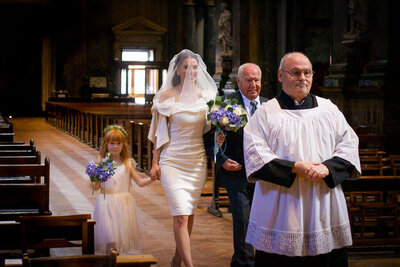 Bride walks down aisle holding fathers hand and flower girls