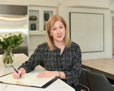 woman writing up a contract sitting in grey business jacket