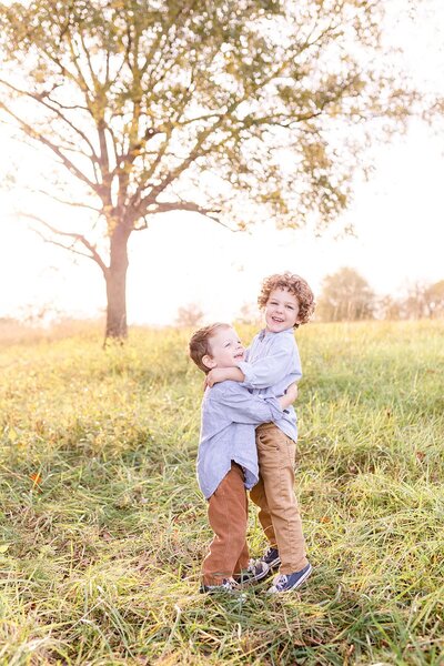 Two brothers hug in green field in fall in Greenville SC