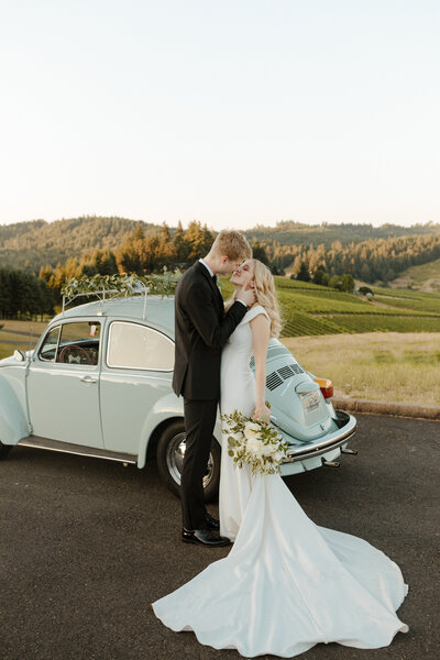 Couple kissing in vinyard with vintage car