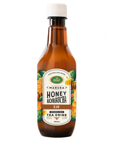 A brown glass bottle of Manuka Honey Kombucha, featuring a label with green and gold accents and the words "Raw Fermented Tea Drink." The label highlights the use of Manuka honey, with vibrant illustrations of honeycombs and leaves, emphasizing the natural and organic ingredients.