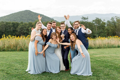 Wedding party photo in Boone, NC of a bride & groom surrounded by their wedding party with the blue ridge mountains in the background.