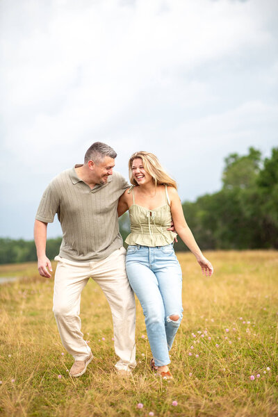 Couple laughing and walking through a field of tall grass at golden hour sunset. Located at Jefferson Equestrian park, FL 