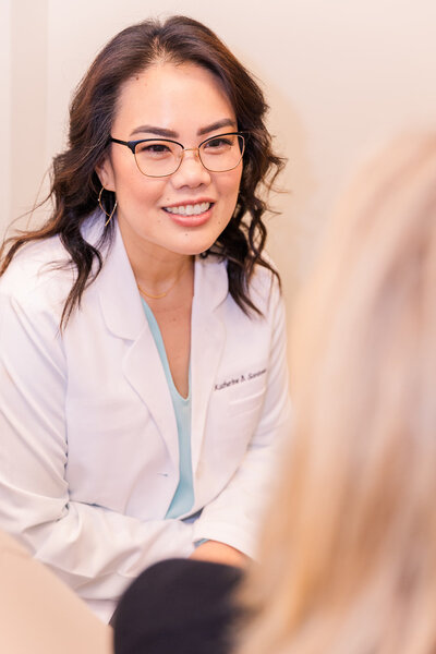 Doctor wearing white coat sitting and talking to a patient during a consultation brand photo Atlanta Laure Photography