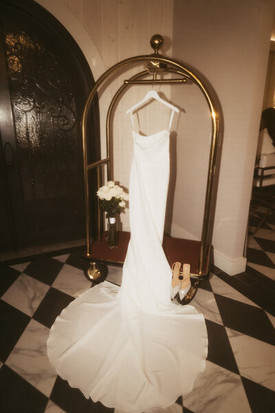 Wedding gown hangs off hotel luggage rack