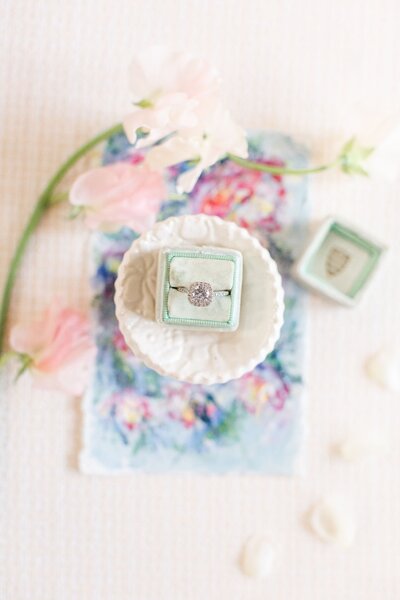 Styled flatlay with florals and engagement ring in green box