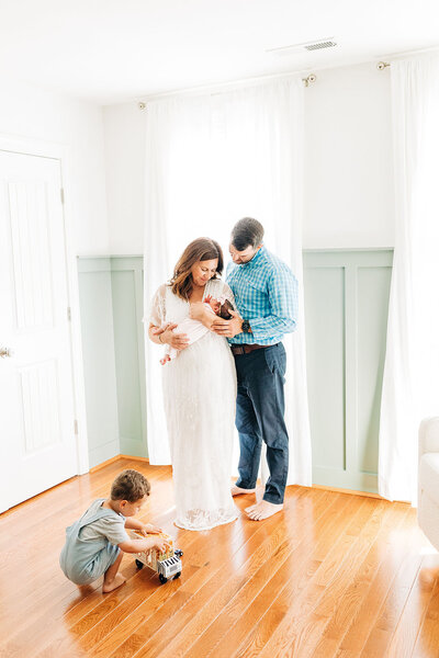 Family of 4 standing in home for Raleigh newborn session