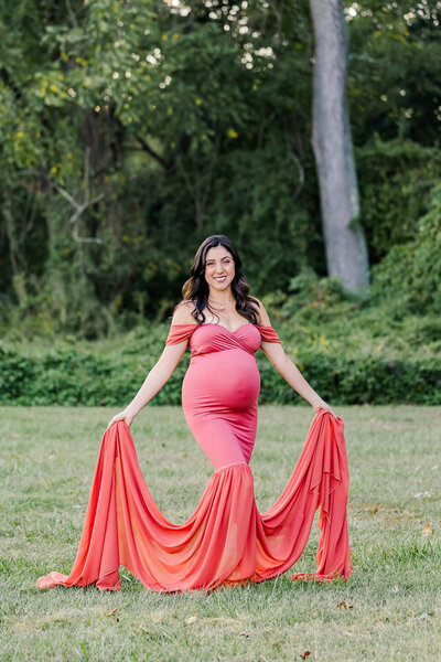 An expecting mother wearing a pink dress posing for portraits in Occoquan, VA.