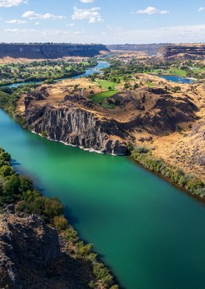 A breathtaking aerial view of the Snake River Canyon, showcasing lush greenery, rugged cliffs, and winding blue waters