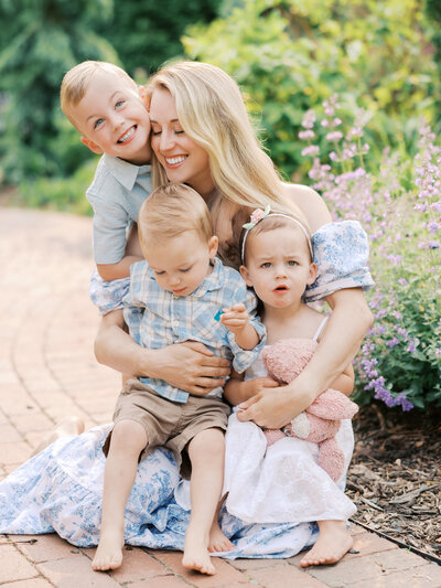Mom snuggles her 3 children at arneson acres park for their edina family photography session with angela watts