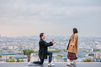 Man kneeling and kissing his partner just after proposing in front of Sacré-Cœur in Montmartre during a romantic Paris proposal photoshoot