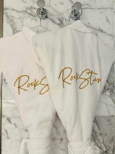 Two white and gold Rock Star robes that are for guests in RockStar and Mega RockStar Suites