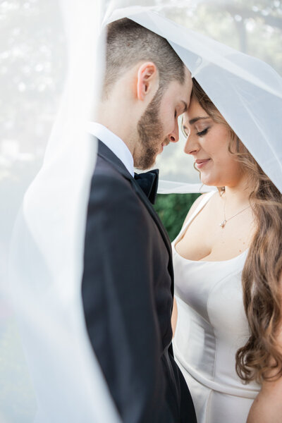 A couple standing under a veil with their foreheads touching
