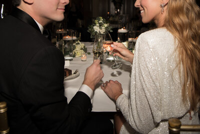 A bride and groom toast one another.