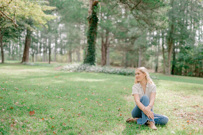 Girl sitting in a field at Seven Springs, a virginia wedding venue