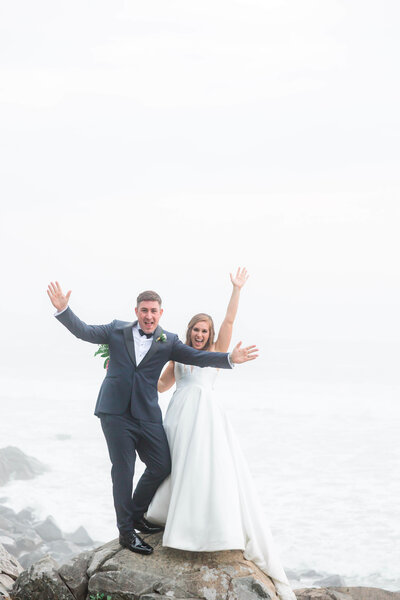 adventurous bride and groom standing on rocks at York Harbor beach for york Inn Wedding  (20)