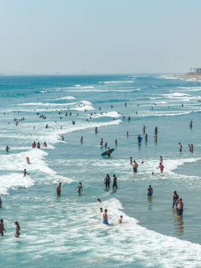 View of surfers and swimmers on a beach in the shore break
