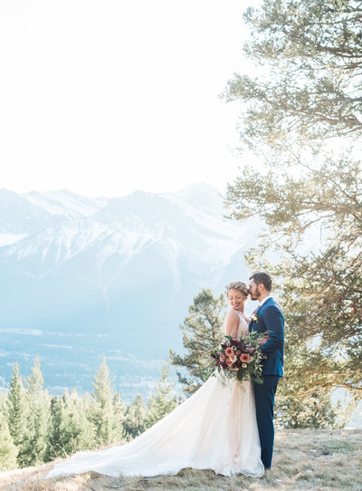 wedding couple standing on a cliff with mountains in background