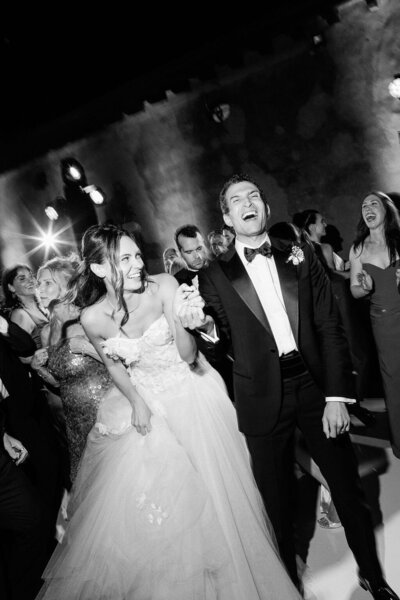 Couple dancing with their guests and laughing at their wedding reception in Tuscany.