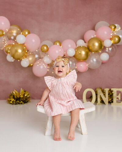 Baby smiling on stool pink and gold decor
