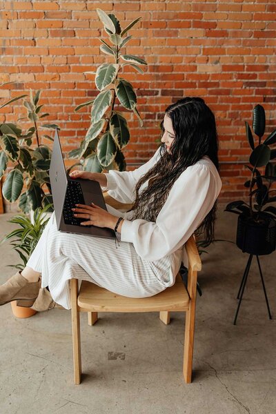 Taysha working on a laptop surrounded by plants.