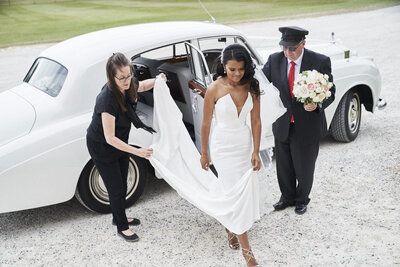 Bride exiting car to arrive at church with wedding planner’s help